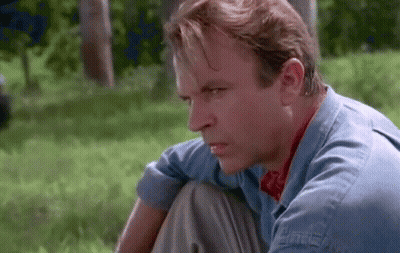 Man In Blue Shirt Sitting In Grass Looking GIF