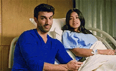 Man In Blue Shirt Sitting Next To Woman In Hospital Bed GIF