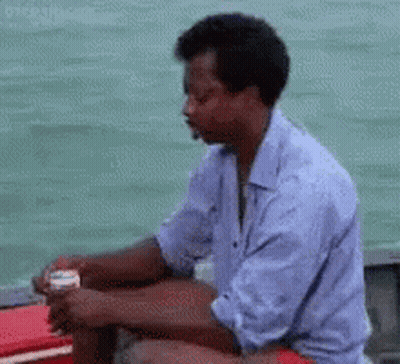 Man In Blue Shirt Sitting On Boat Looking At Water GIF