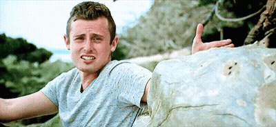 Man In Blue Shirt Sitting On Rock Making Face GIF