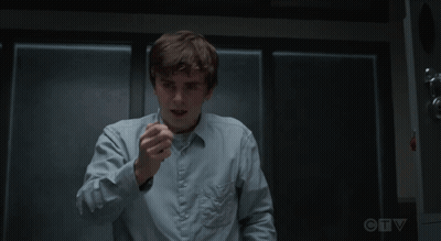 Man In Blue Shirt Sitting With Hands Folded In Dark Room GIF
