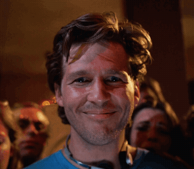 Man In Blue Shirt Smiling In Front Of Crowd GIF