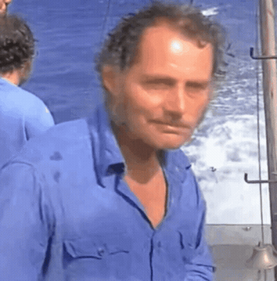 Man In Blue Shirt Standing At Ocean GIF