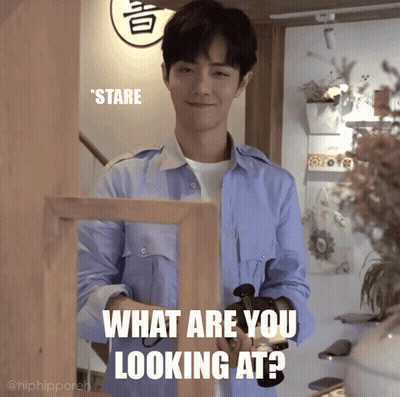 Man In Blue Shirt Standing Before What Are You Looking At Sign GIF