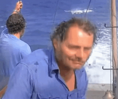 Man in Blue Shirt Standing by Ocean