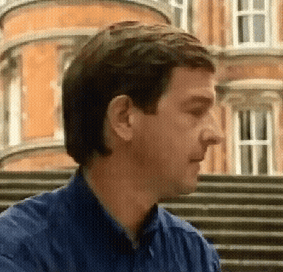Man In Blue Shirt Standing In Front Of Building GIF