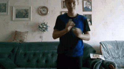 Man In Blue Shirt Standing In Front Of Couch GIF