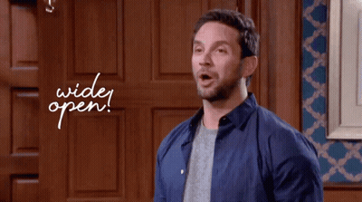 Man In Blue Shirt Standing In Front Of Door Saying Wide Open GIF