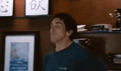 Man In Blue Shirt Standing In Front Of Shelf With Picture GIF