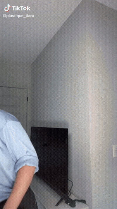 Man In Blue Shirt Standing In Front Of TV With TikTok Watermark GIF