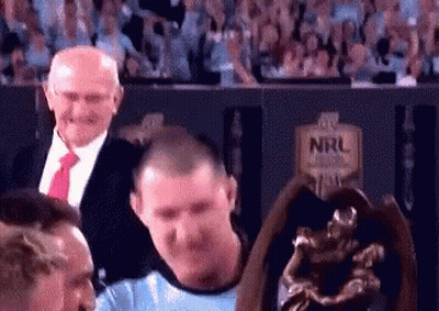 Man In Blue Shirt Standing Next To Trophy In Stadium GIF