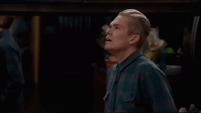 Man In Blue Shirt Standing With Mouth Open In Dark Room GIF