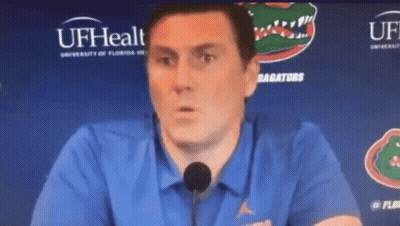 Man In Blue Shirt Talking Into Microphone At UFHealth Sign GIF
