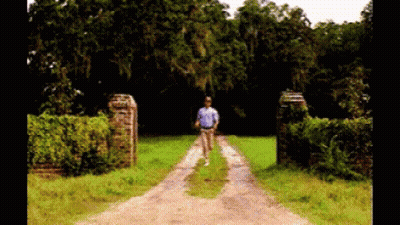 Man In Blue Shirt Walking Down Dirt Road GIF