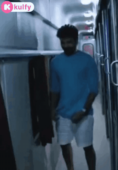 Man In Blue Shirt Walking Down Hallway With Kulfy Logo GIF