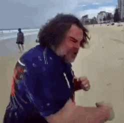 Man In Blue Shirt Walking On Beach GIF