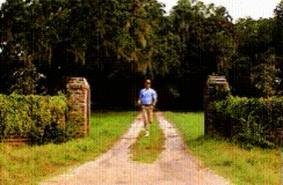 Man In Blue Shirt Walking Past Welcome Sign GIF