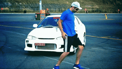 Man in Blue Shirt Walking Past White Car License Plate TO05XY