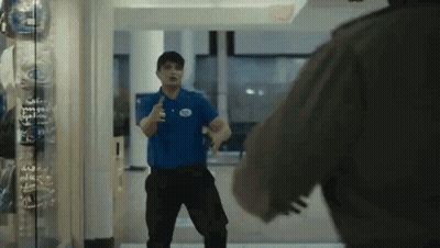 Man In Blue Shirt With White Circle Standing In Hallway GIF