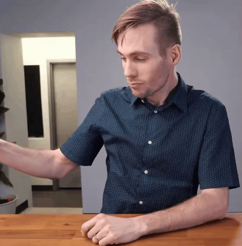 Man In Blue Shirt With White Polka Dots Sitting At Table GIF