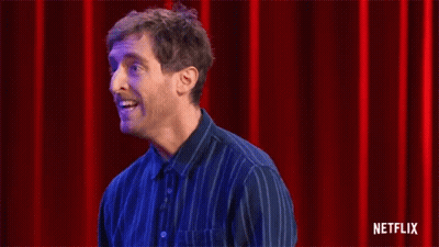 Man In Blue Striped Shirt Clapping Before Red Curtain GIF