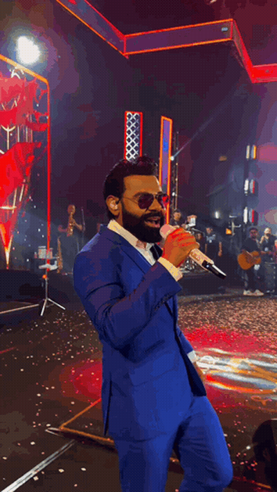 Man In Blue Suit And Mask Singing On Stage GIF