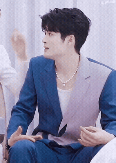Man in Blue Suit and Pearl Necklace Talking to Another Man
