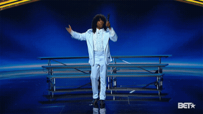 Man In Blue Suit Holding Microphone In Front Of Bet Star GIF