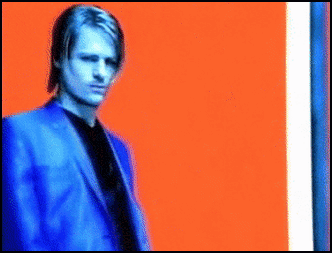 Man In Blue Suit In Front Of Orange And Blue Background GIF