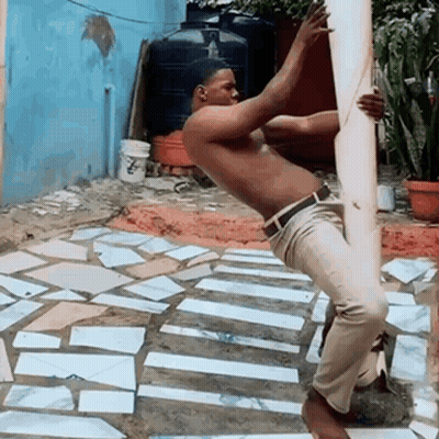 Man In Blue Sweater And White Pants By Parking Lot Fence GIF