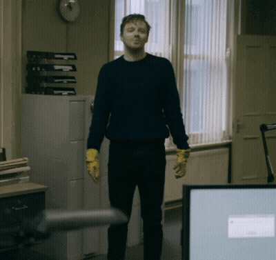 Man In Blue Sweater And Yellow Gloves By Window GIF