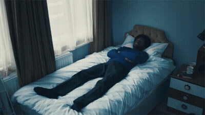 Man In Blue Sweater Lying On Bed GIF