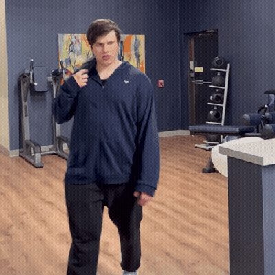 Man In Blue Sweatshirt With White Eagle Walking In Gym GIF