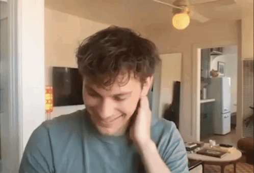 Man In Blue T-Shirt Smiling In Living Room GIF