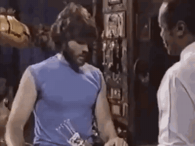 Man In Blue Tank Top Next To Man Holding Bottle GIF