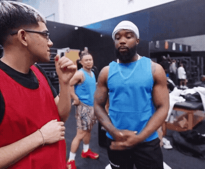 Man In Blue Tank Top Talking To Man In Red Vest GIF