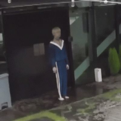 Man In Blue Tracksuit Holding Cane In Front Of Building GIF