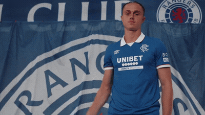 Man In Blue Unibet Shirt In Front Of Rangers Banner GIF