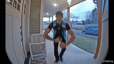 Man In Blue Vest On Porch Next To White Rocking Chair GIF