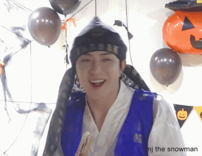 Man In Blue Vest Smiling With Balloons And Pumpkin GIF