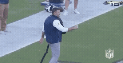 Man In Blue Vest Talking On Football Field GIF