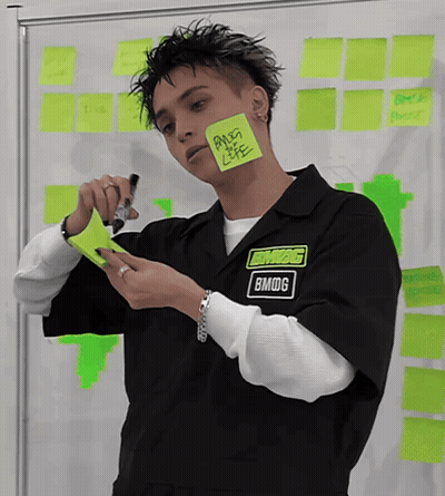 Man In Bmdg Shirt Holding Paper Over Face GIF