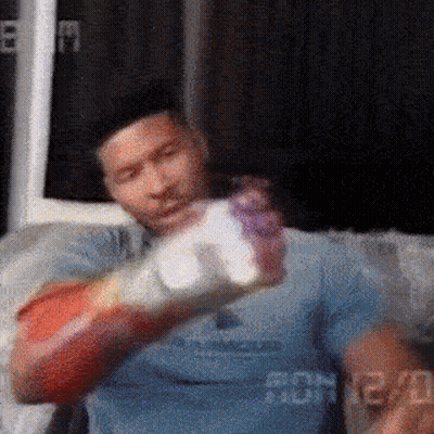 Man In Boxing Gloves Sitting On Couch Holding Bottle GIF