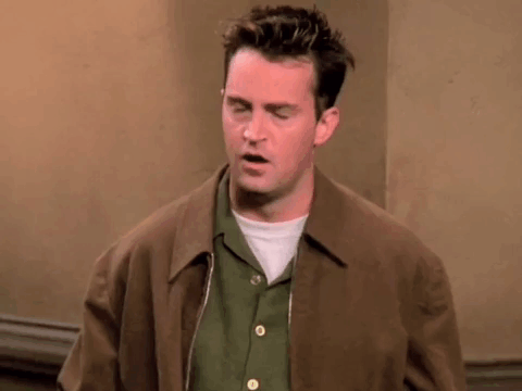 Man In Brown Jacket And Green Shirt Standing In Room GIF