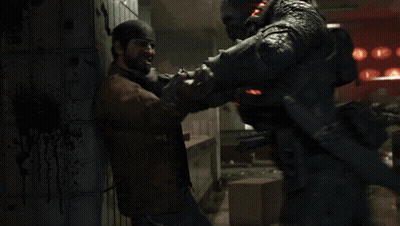 Man In Brown Jacket Holding Another Man's Neck In Dark Room GIF