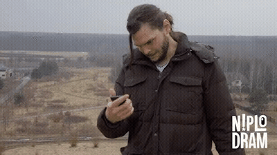 Man In Brown Jacket Looking At Phone Nipic Dram GIF