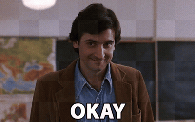 Man In Brown Jacket Saying Okay In Classroom GIF