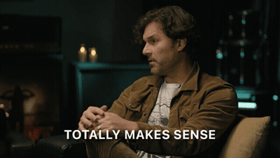 Man In Brown Jacket Sits On Couch Saying Totally Makes Sense GIF