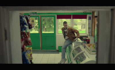 Man In Brown Jacket Sits On Counter With Exit Only Sign GIF