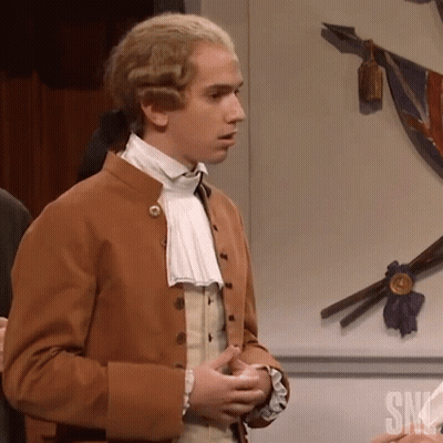 Man In Brown Jacket Standing In Front Of SNL Wall GIF